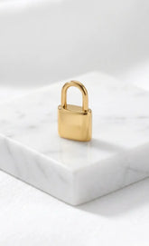 Filigranes, hochglanzpoliertes Liebesschloss-Charm aus Edelstahl 18k vergoldet, stehend auf einem eleganten Marmorblock