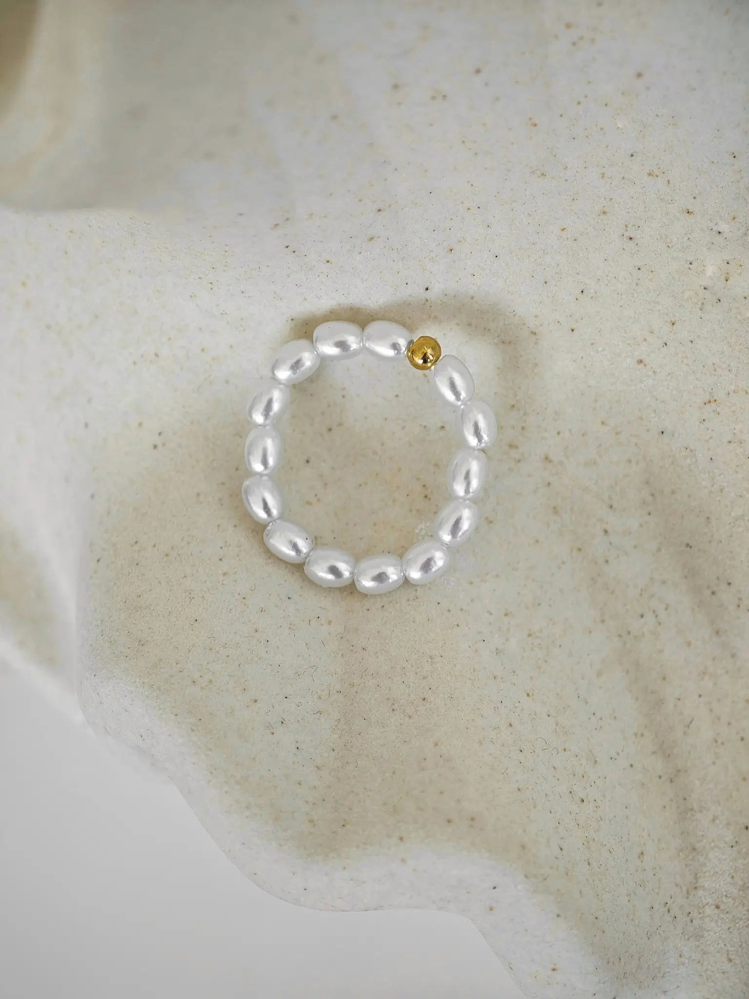 Perlenring mit Edelstahl-Kugel in der Mitte, umgeben von zarten Mini-Perlen