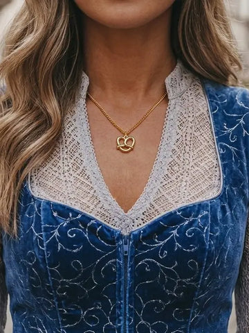 Goldener Brezel Charm Anhänger aus 18K vergoldetem Edelstahl an einer Frau im blauer  Tracht