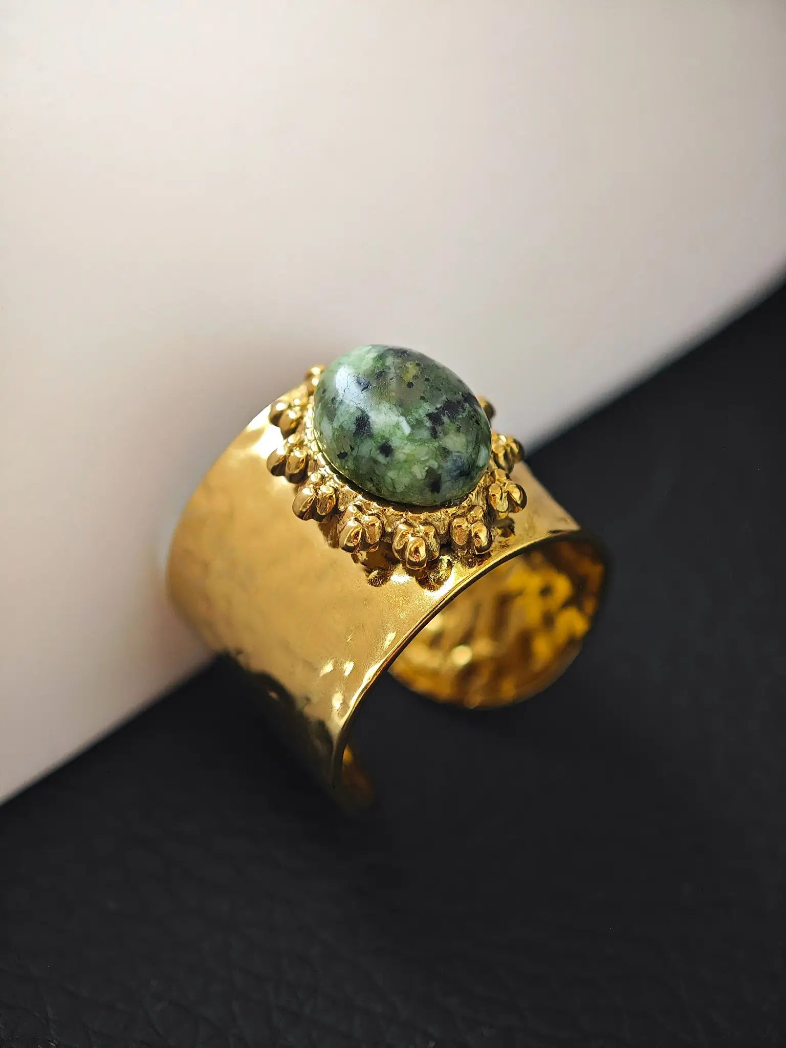 Goldener Ring mit grün gesprenkeltem Stein und Sonnenmotiv in Schalenform