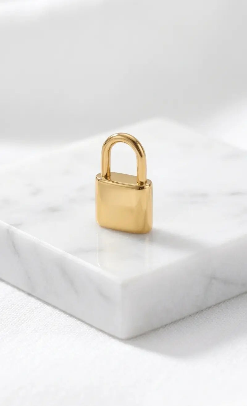 Filigranes, hochglanzpoliertes Liebesschloss-Charm aus Edelstahl 18k vergoldet, stehend auf einem eleganten Marmorblock