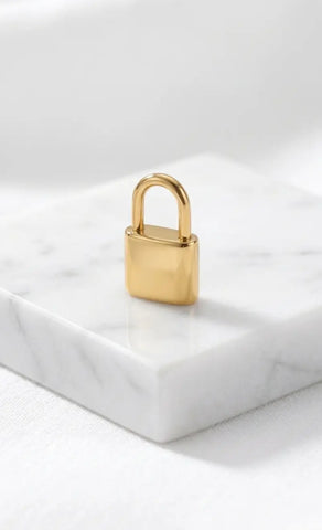 Filigranes, hochglanzpoliertes Liebesschloss-Charm aus Edelstahl 18k vergoldet, stehend auf einem eleganten Marmorblock
