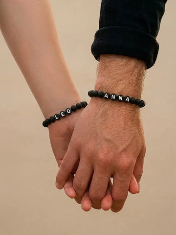 Namensarmband Set mit Wunschnamen aus Naturstein-Onyxperlen, getragen am Handgelenk eines Paares Hand in Hand