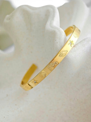 Goldener Armreif mit graviertem Seestern, Muschel, Seepferdchen und kleinen Zirkonia-Steinen
